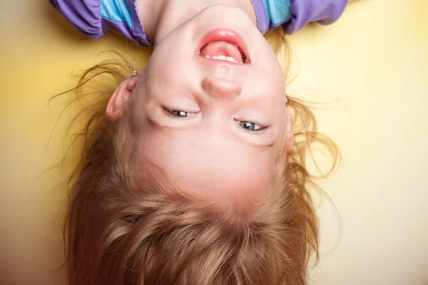 Little girl upside down against yellow background — Stock Photo, Image