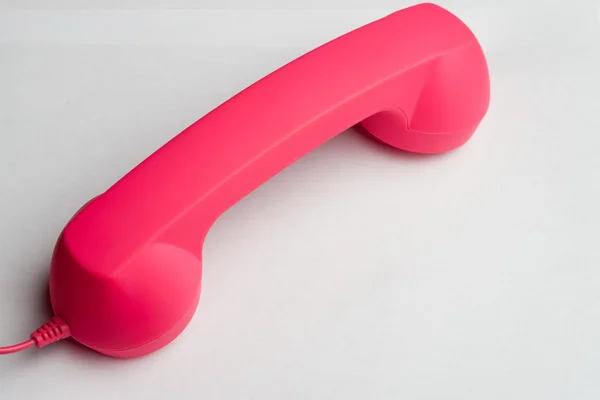 Telefone rosa quente virado para baixo na superfície branca — Fotografia de Stock