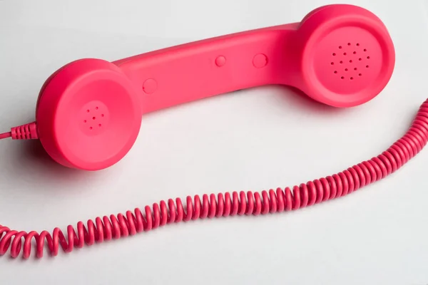 Rózsaszín telefon és kábel fehér felületre — Stock Fotó