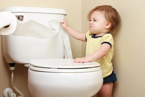 Ornery baby zieht Toilettenpapier von der Rolle lizenzfreie Stockfotos