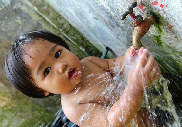 Kleines Kind spielt im Wasserhahn — Stockfoto