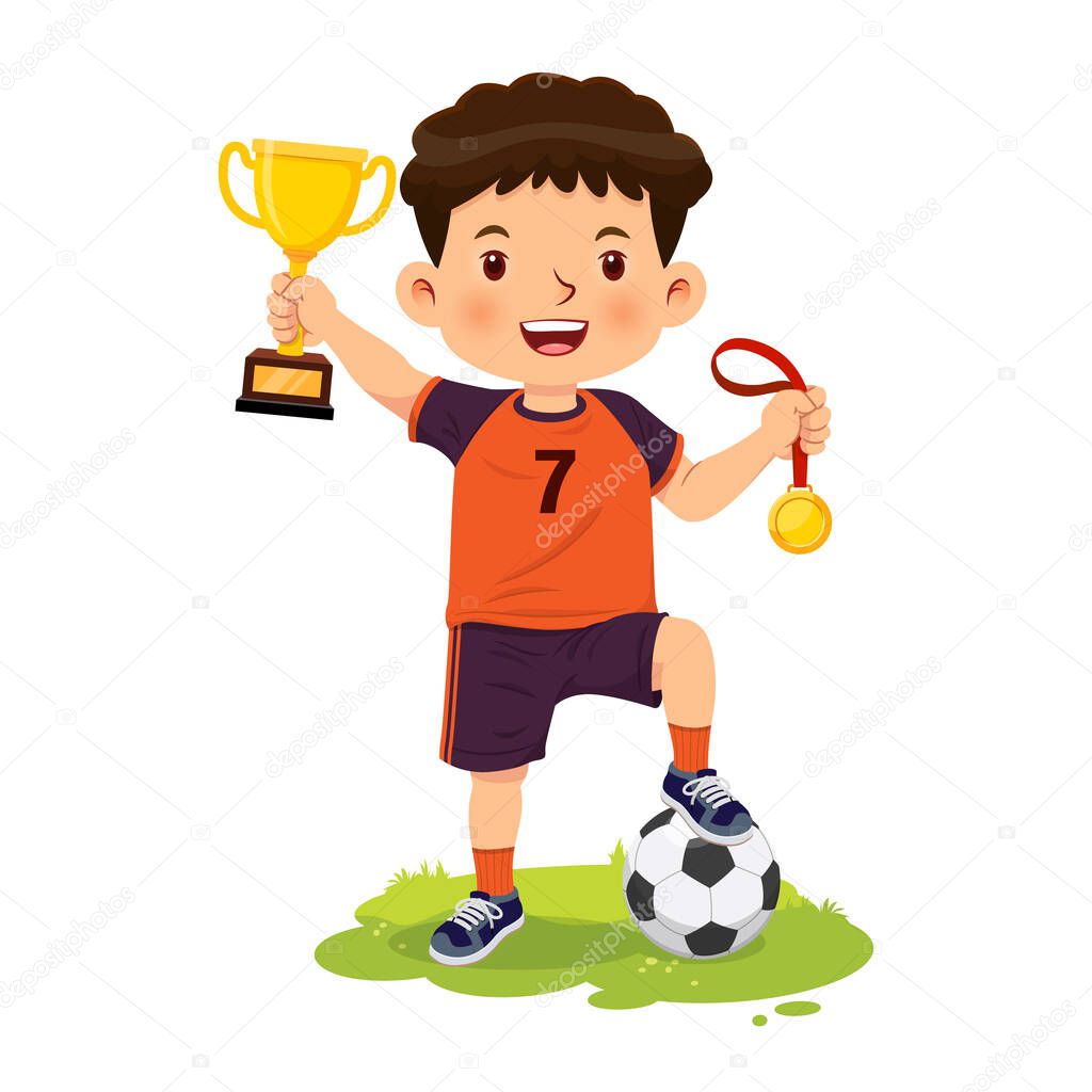 Happy smiling boy stands holding gold medal and trophy from winning football games.