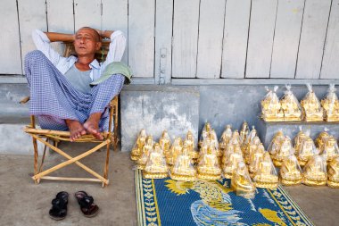YANGON FEBRUARY 2010. A gold Buddha statues seller taking a nap while waiting for sales at a pavement by the Shwedagon Pagoda on February 7th 2010
