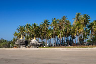 Two golden pagodas sitting on top of rocks found on the beach of Ngwe Saung, west coast of Myanmar. clipart