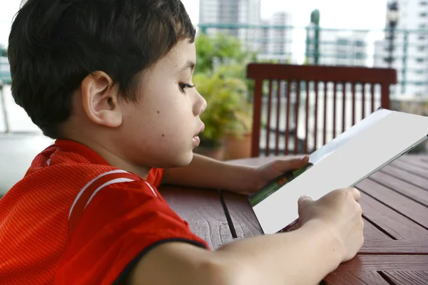 Jonge jongen verdiept tijdens het lezen van een boek. — Stockfoto
