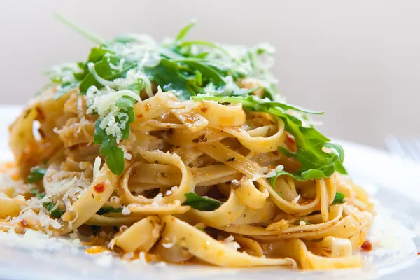 Läckra fettucine pasta med soltorkade tomater och ruccola lämnar — Stockfoto