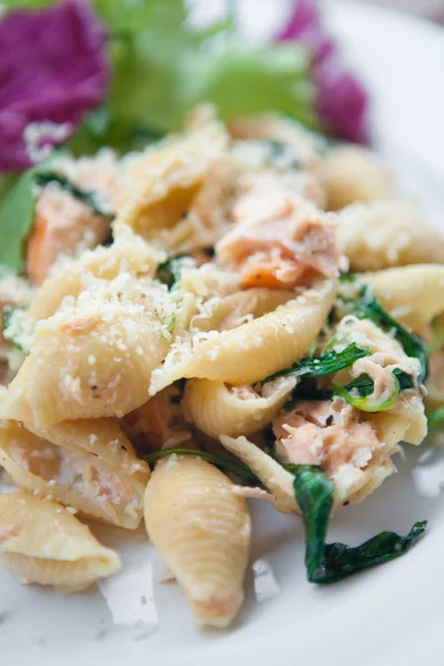 Pasta with salmon, spinach and cream, with fresh salad on the side. — Stock Photo, Image