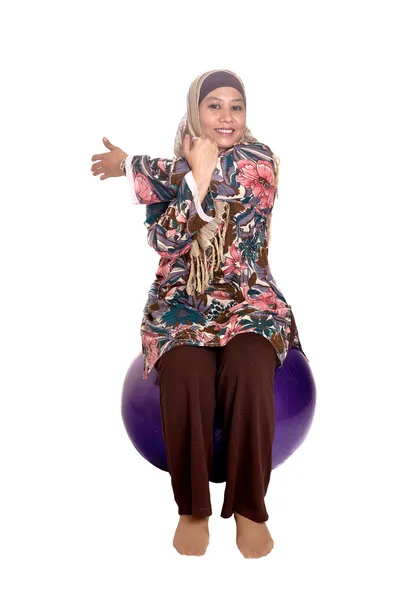 Muslim woman on fit ball while stretching her tricep as part of healthy lifestyle concept — Stock Photo, Image
