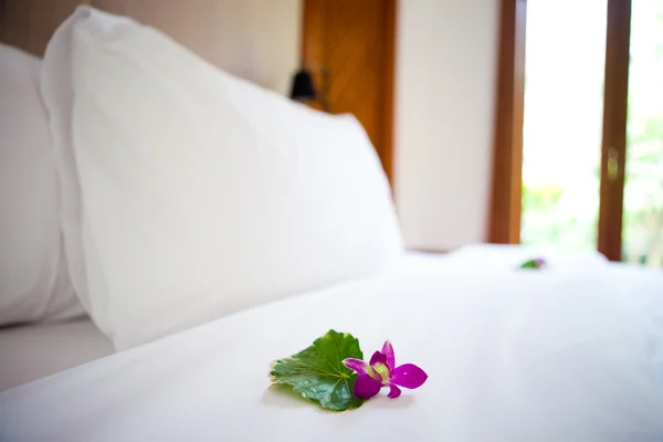 Schönes frisch gemachtes Bett in den Tropen mit frischer Orchidee — Stockfoto