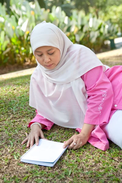 Όμορφη ώριμη μουσουλμάνα απολαμβάνοντας το πάρκο με ένα βιβλίο — Φωτογραφία Αρχείου