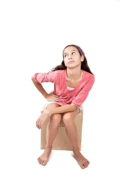 Young girl sitting on empty cardbox box, on white background Royalty Free Stock Photos
