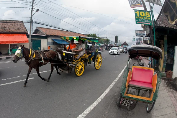 Jogjakarta 5 월 15 일입니다. 그려 말 마차 Jogja의 바쁜 거리에서 교통의 인기 있는 방법입니다. 거리에서 말 그려진 마차에 가족 로열티 프리 스톡 이미지