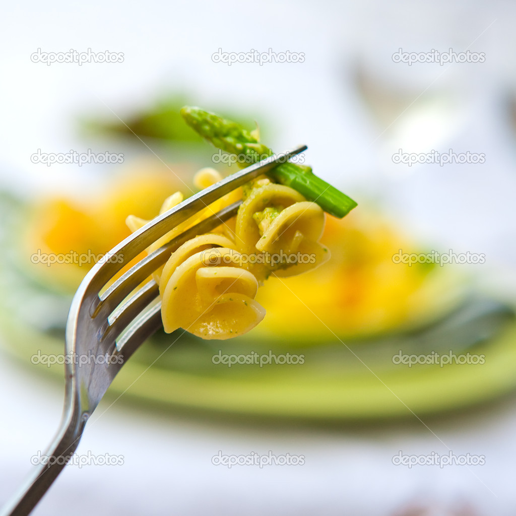 Pasta with basil pesto and asparagus on a fork