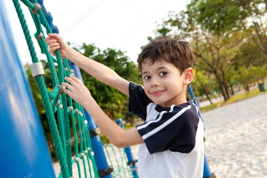 Young boy enjoying the playground climbing activity.