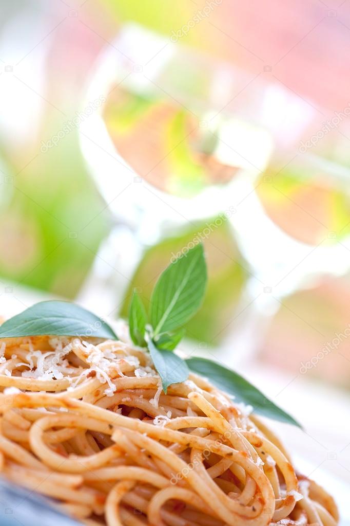 A plate of spaghetti with tomato sauce in an outdoor setting.