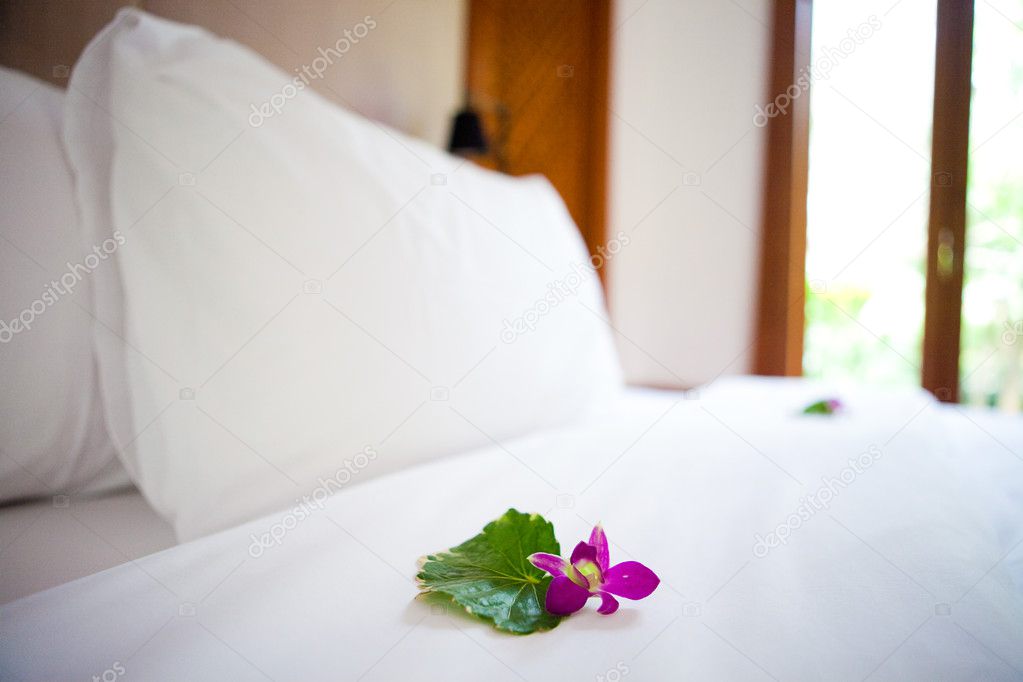 Beautiful freshly made bed in the tropics with fresh orchid