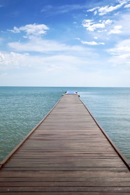 Wooden boardwalk above water out towards open ocean clipart
