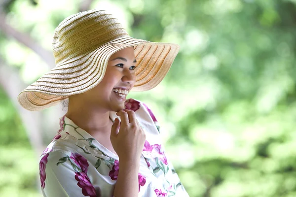 Beautiful Asian girl with wide brim straw hat in the park — Stock Photo, Image