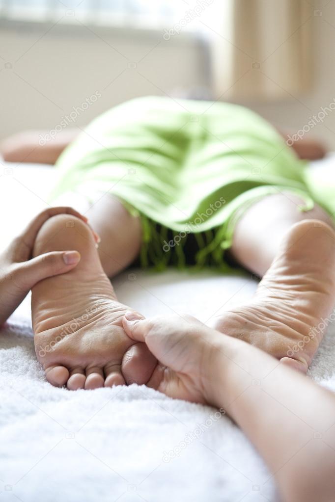 :Woman receiving foot reflexology by therapist