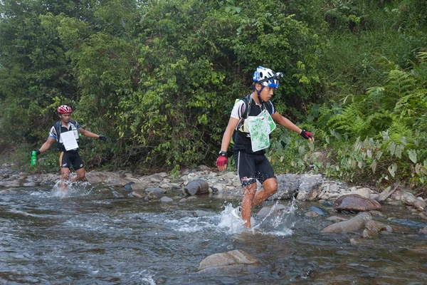 SABAH, MALASIA - 2 DE ABRIL. Un corredor de un equipo participante hace su camino a lo largo de un río en la carrera de la madrugada para el Sabah Adventure Challenge, 2 de abril de 2010, Sabah, Malasia . — Foto de Stock