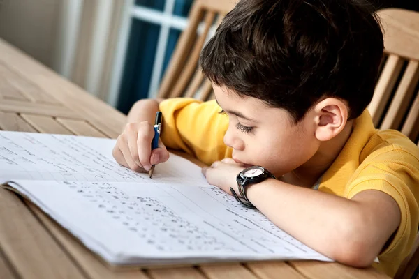 Jonge jongen zijn huiswerk thuis. — Stockfoto