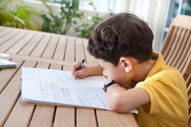 genç çocuk ev ortamında kendi ödevlerini yapıyor