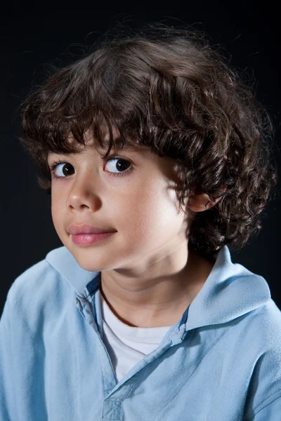 Lindo niño pequeño con grandes ojos y una pequeña sonrisa mostrando cara de curiosidad . — Foto de Stock