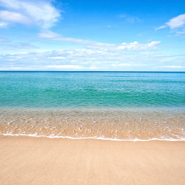 Bella spiaggia di sabbia con acqua calma contro il cielo blu . — Foto Stock