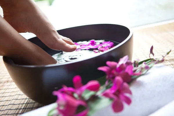 Weibliche Füße in Orchideen-Wellnessschale — Stockfoto