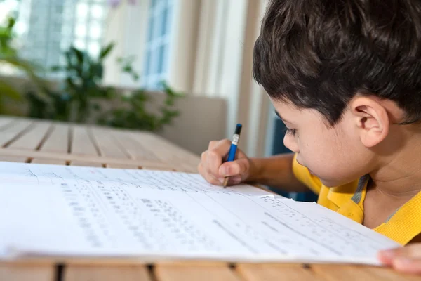 Мальчик делает домашнее задание в домашней обстановке — стоковое фото
