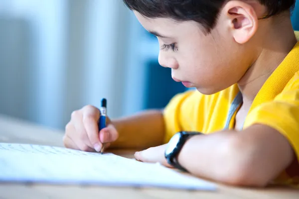 Jonge jongen zijn huiswerk in een thuisomgeving — Stockfoto