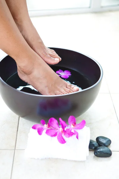 Pés de mulher em tigela spa pé com orquídeas — Fotografia de Stock