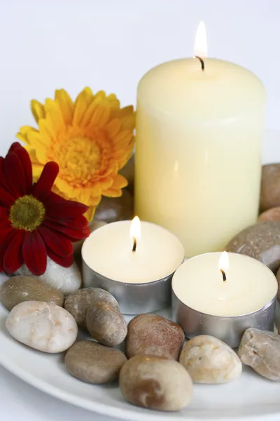 Kaarsen met keien en bloemen klaar voor wellness instelling. — Stockfoto