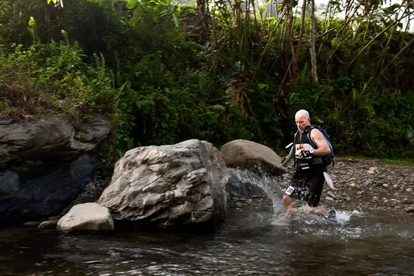 Un coureur d'une équipe participante fait son chemin le long d'une rivière — Photo