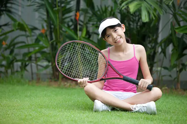 Menina com uma raquete de tênis e bola de tênis no jardim . — Fotografia de Stock