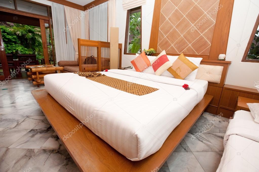 Beautiful kingsize bed in a tropical hotel bedroom.