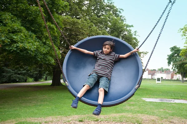 Young boy in playground swing — Stock Photo, Image