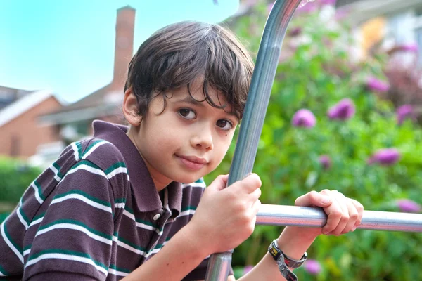 Hermoso joven en un marco de escalada en el jardín — Foto de Stock