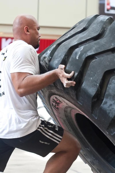 Strongman Szulejmán Ismail kísérlet a hat versenyző alkalommal 350 kg gumiabroncs flip — Stock Fotó