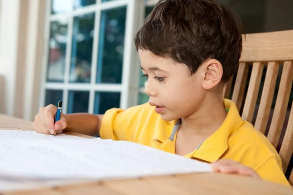 Красивый мальчик делает домашнее задание дома — стоковое фото