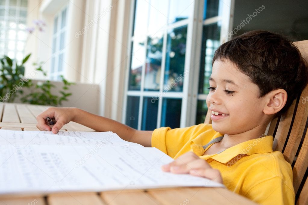 Beautiful young boy doing his homework at home
