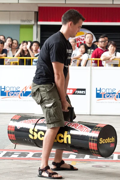 TOA PAYOH, SINGAPORE - MARCH 24 : An male audience tries out the 120kg log used for the log walk in the Strongman Challenge 2012 on March 24, in Toa Payoh Hub, Singapore. — Stock Photo, Image