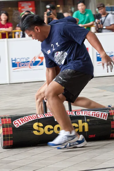 TOA PAYOH, SINGAPORE - MARCH 24 : Contenders for the under 20s in the 120kg log walk category in the Strongman Challenge 2012 on March 24, in Toa Payoh Hub, Singapore. — Stock Photo, Image