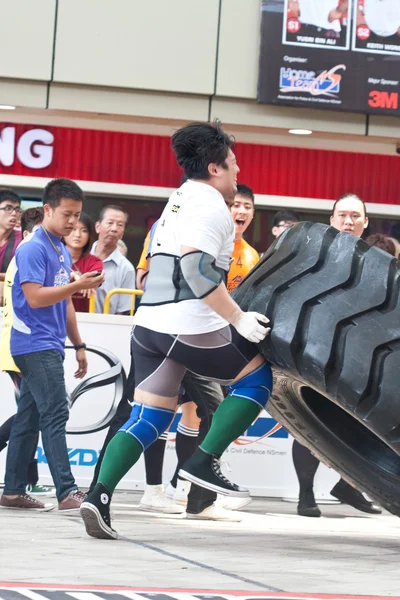 TOA PAYOH, SINGAPORE - MARCH 24 : Contender for Strongman Samuel Lim attempting the six times 350kg tyre flip category in the Strongman Challenge 2012 on March 24, in Toa Payoh Hub, Singapore. — Stock Photo, Image