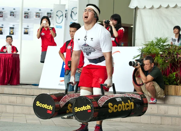 TOA PAYOH, SINGAPORE - MARCH 24 : Contender for Strongman Benjamin Soh attempts the 2 times 120 log walk in the Strongman Challenge 2012 on March 24, in Toa Payoh Hub, Singapore. Royalty Free Stock Images