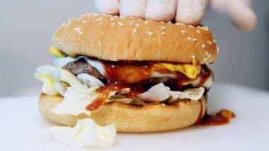 Masada taze lezzetli bir burger. Lezzetli dolgulu sıcak hazır burger. Lezzetli kırmızı soslu iştah açıcı hamburger aşağı akıyor. Yakın plan..