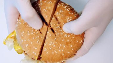 Taze lezzetli burger. Şef, iştah açıcı dolguyla ikiye bölünmüş lezzetli hamburgerler gösteriyor. Hamburgeri hazır et. Yakın plan..