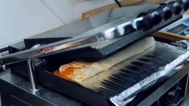 Izgara kızarmış shawarma. Aşçı Shawarma 'yı halleder. Izgara makinesinde nefis pita. Restoranda pide pişirmek. Fast food pişiriyorum..