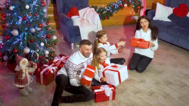 圣诞节带着礼品盒的孩子和父母 圣诞前夕 一家人带着小孩聚在圣诞树旁 享受着礼物 新年庆祝活动 寒假活动 顶部视图 — 图库视频影像