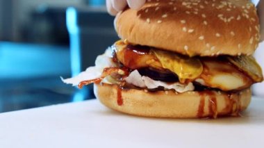Hamburger yapıyorum. Şef lezzetli hamburgerleri pişirmeyi bitirdi. Sofrada iştah açıcı dolgulu sulu hamburger. Yakın plan..